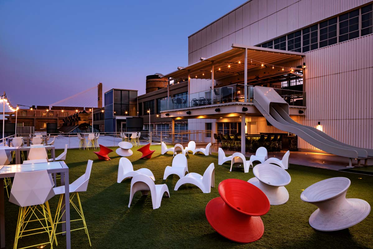 a building with a slide and chairs on a lawn