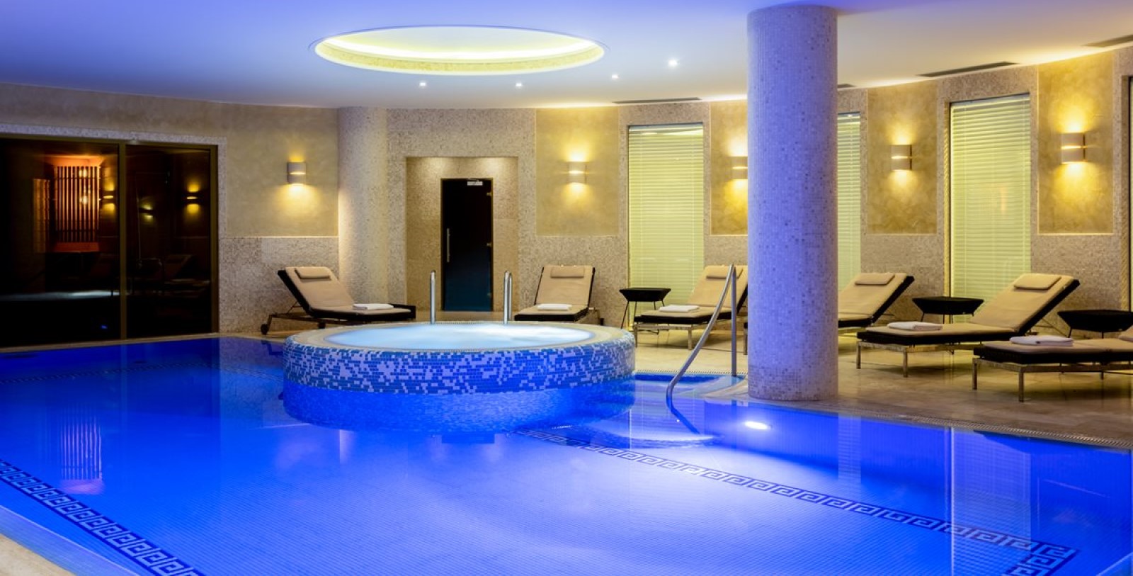 a pool with a round tub and chairs