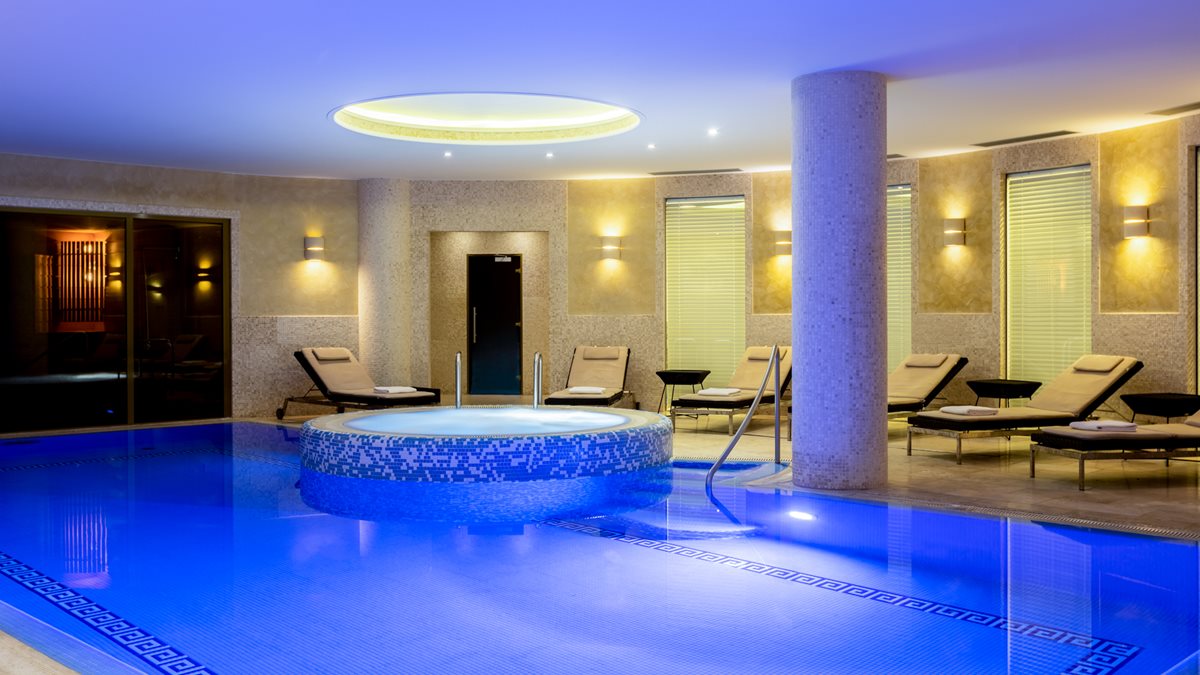 a pool with a round tub and chairs in a room