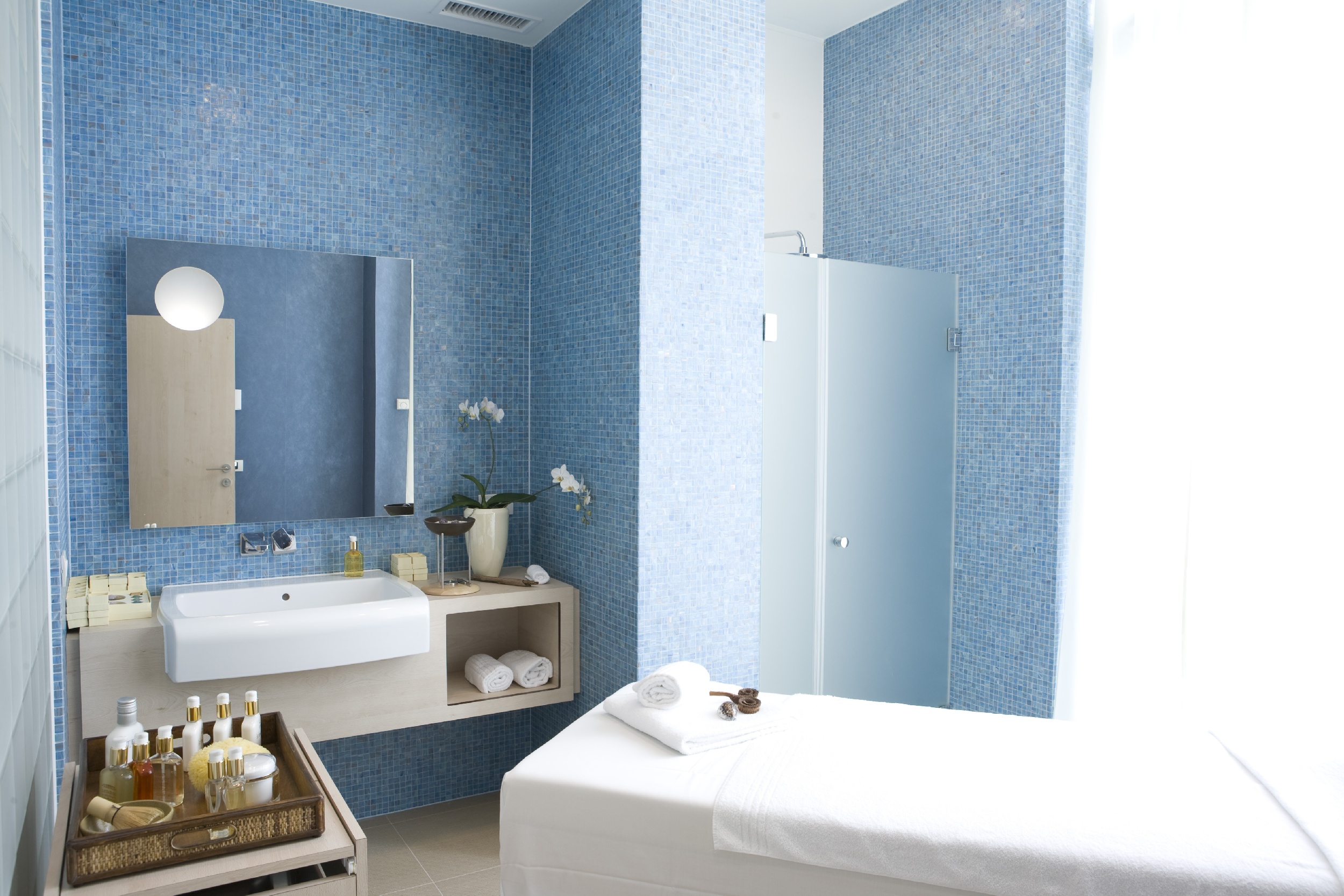 a bathroom with a white bed and blue tile walls