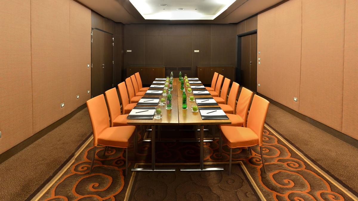 a conference room with orange chairs and a table with green bottles