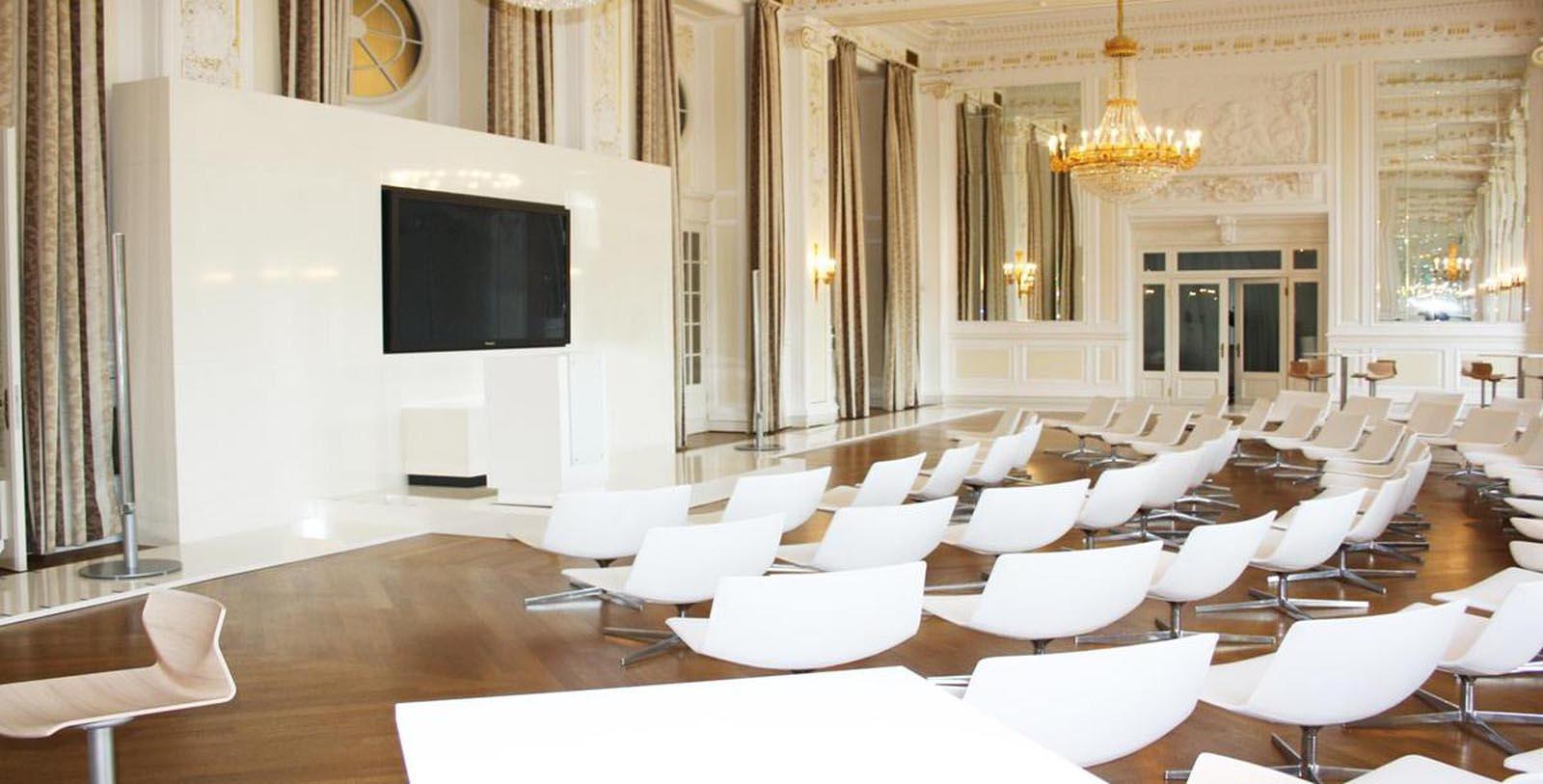 a room with white chairs and a television