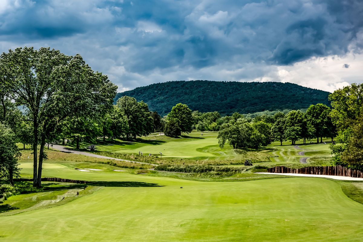 a golf course with trees and a hill in the background