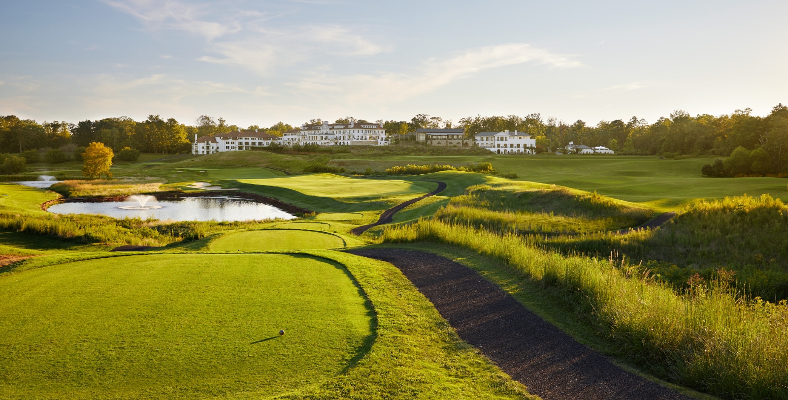 a golf course with a pond and a building in the background