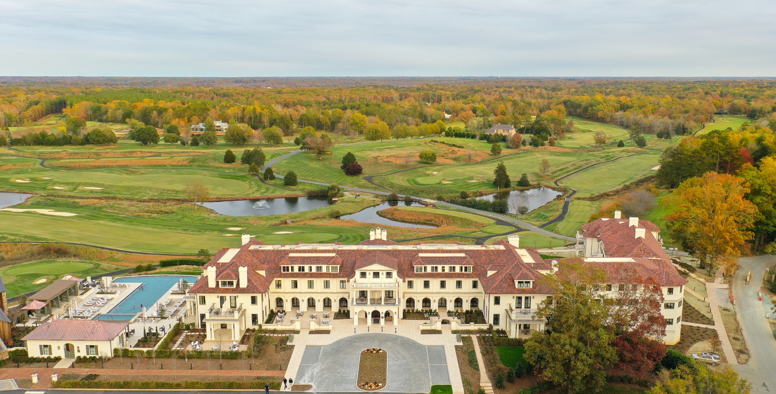 a large white building with a pond and trees in the background