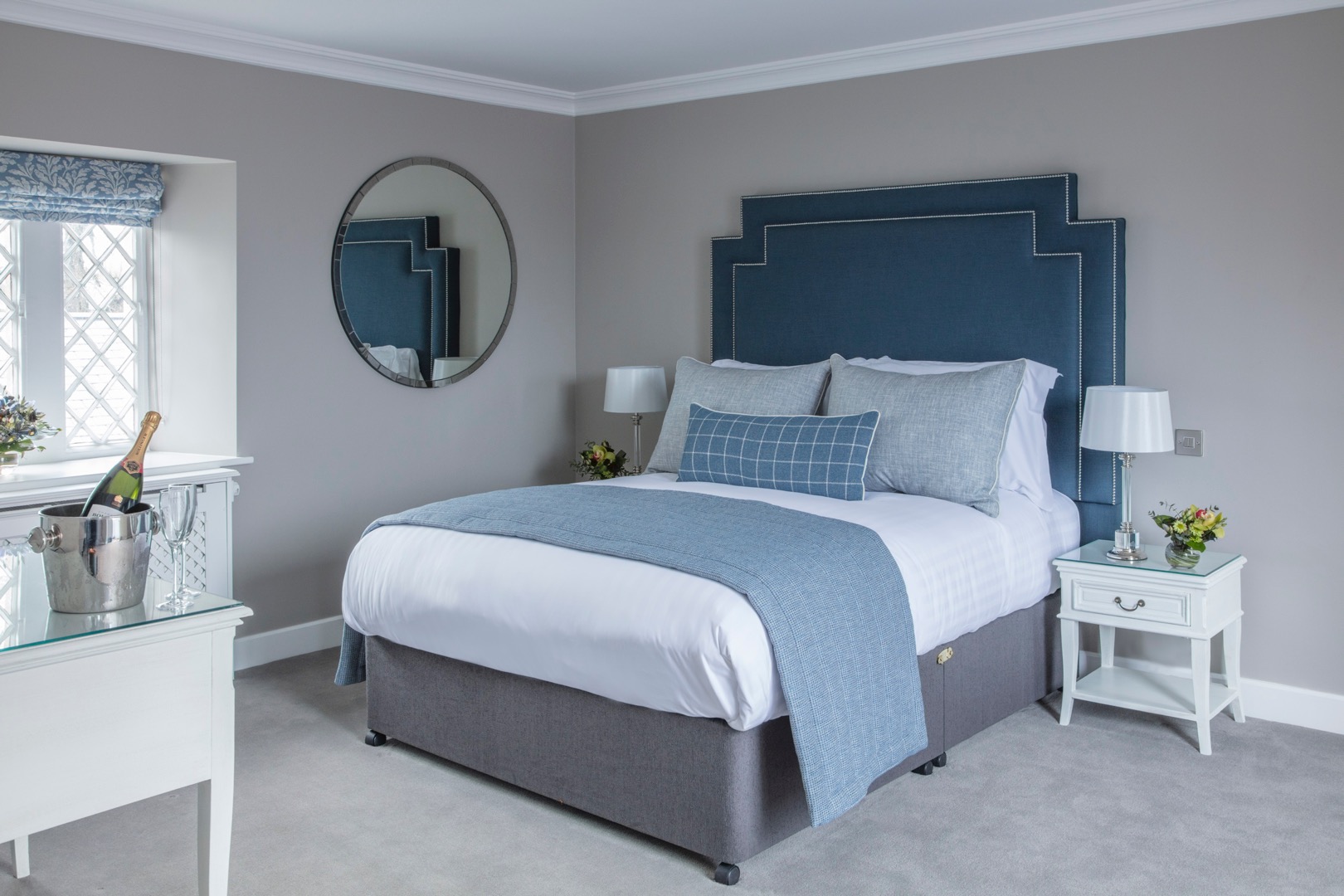 a bed with a blue headboard and a mirror