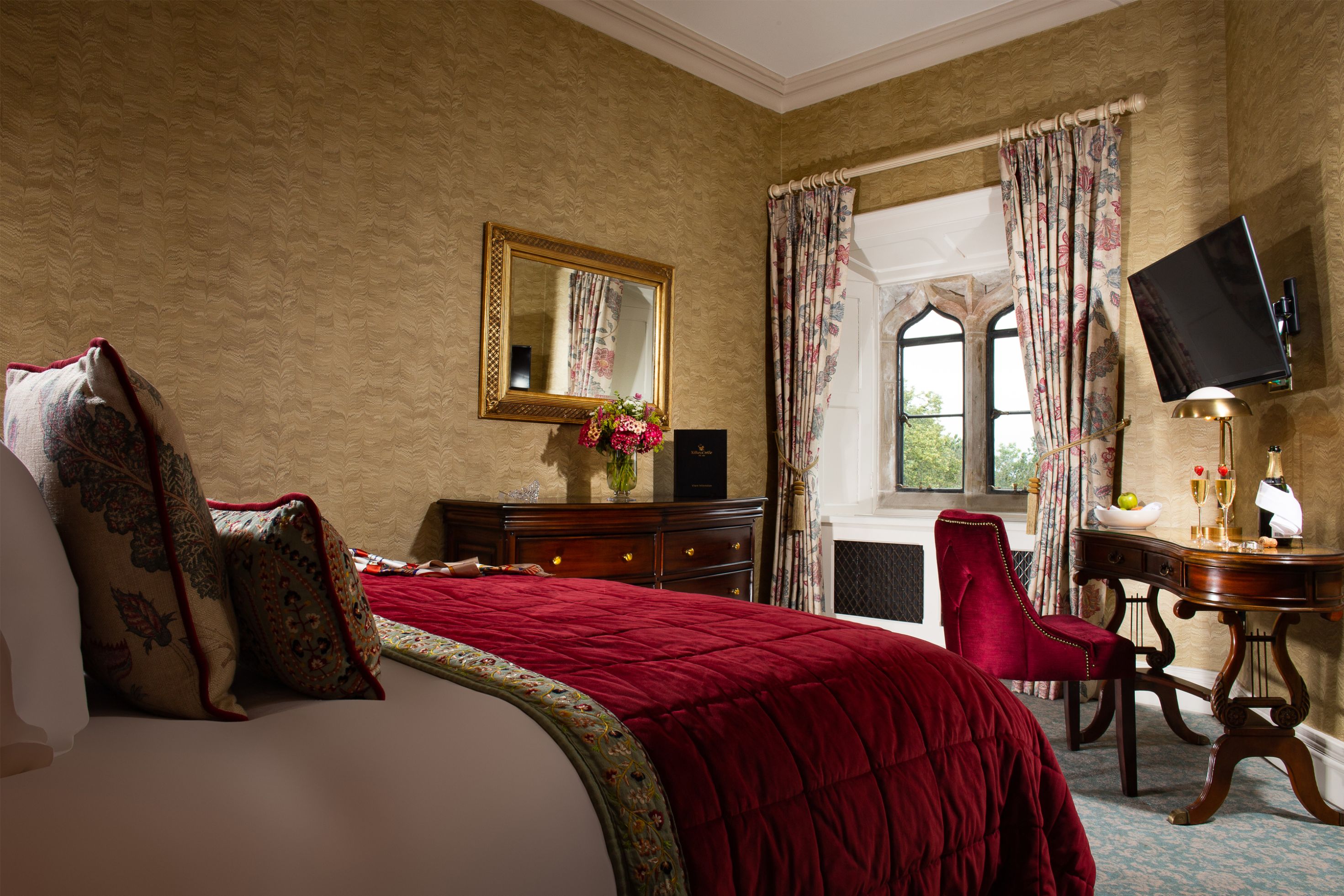 a bedroom with a red bed and a mirror