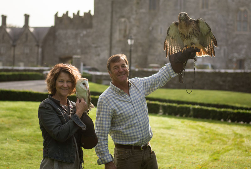 a man and woman holding an eagle on their hand