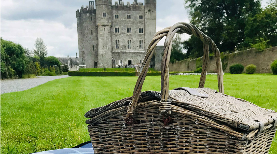 a picnic basket on a blanket in front of a castle