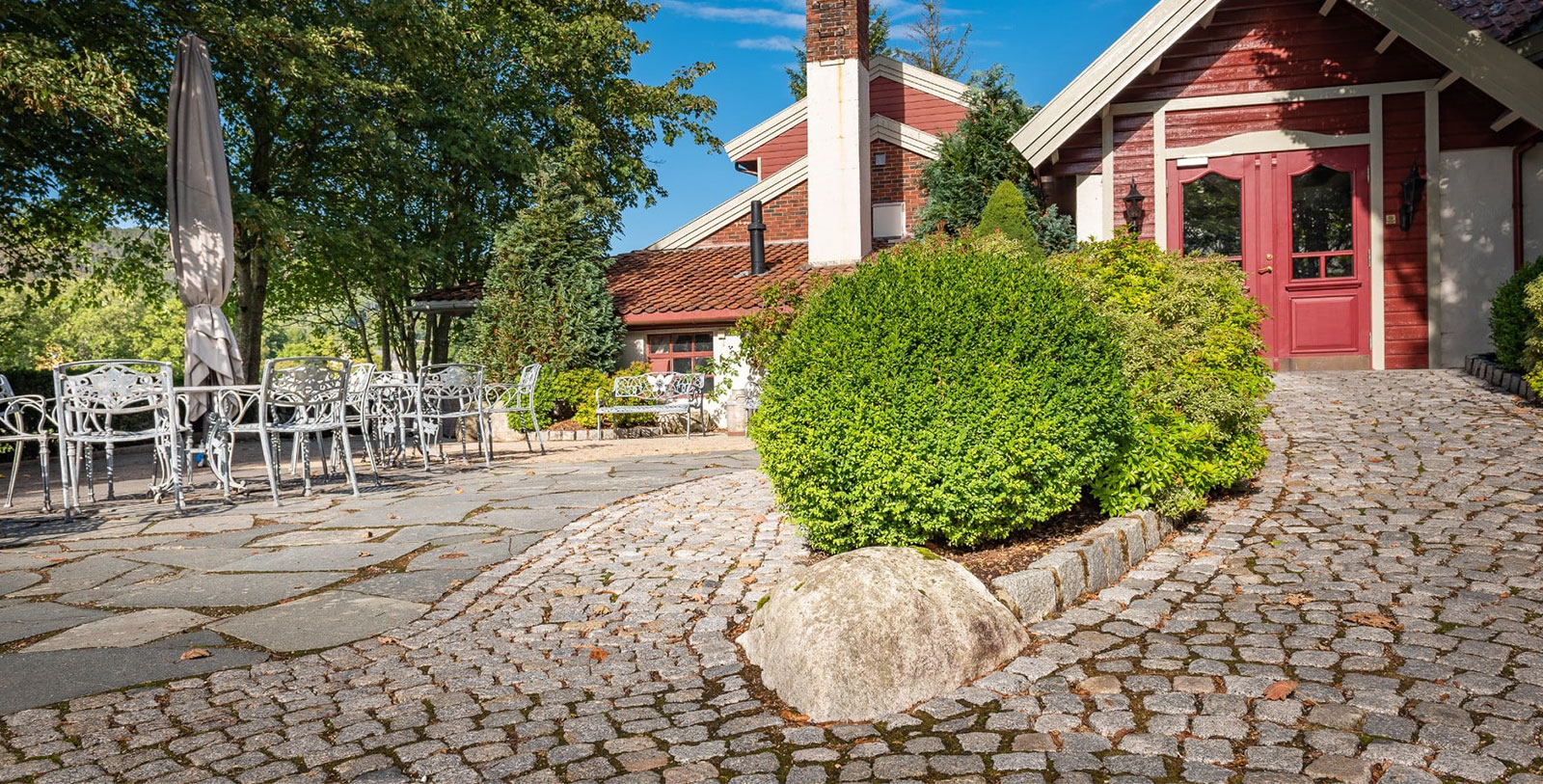 a stone walkway with a brick chimney and bushes