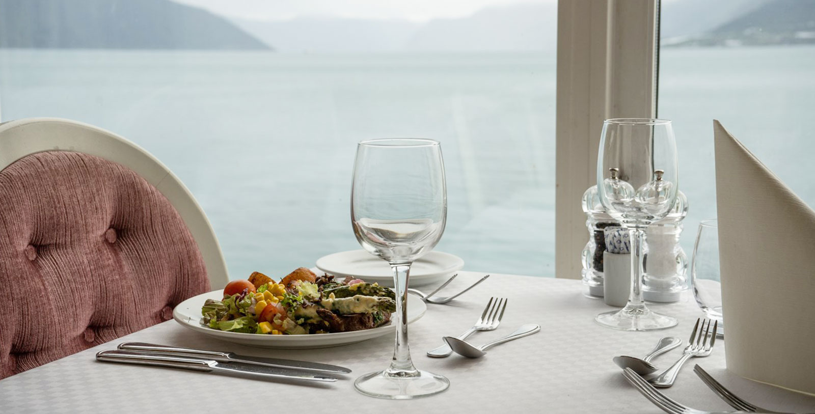 a plate of salad and wine glasses on a table