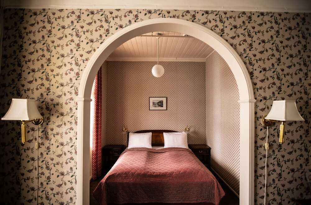 a bed with a red blanket and a white lamp