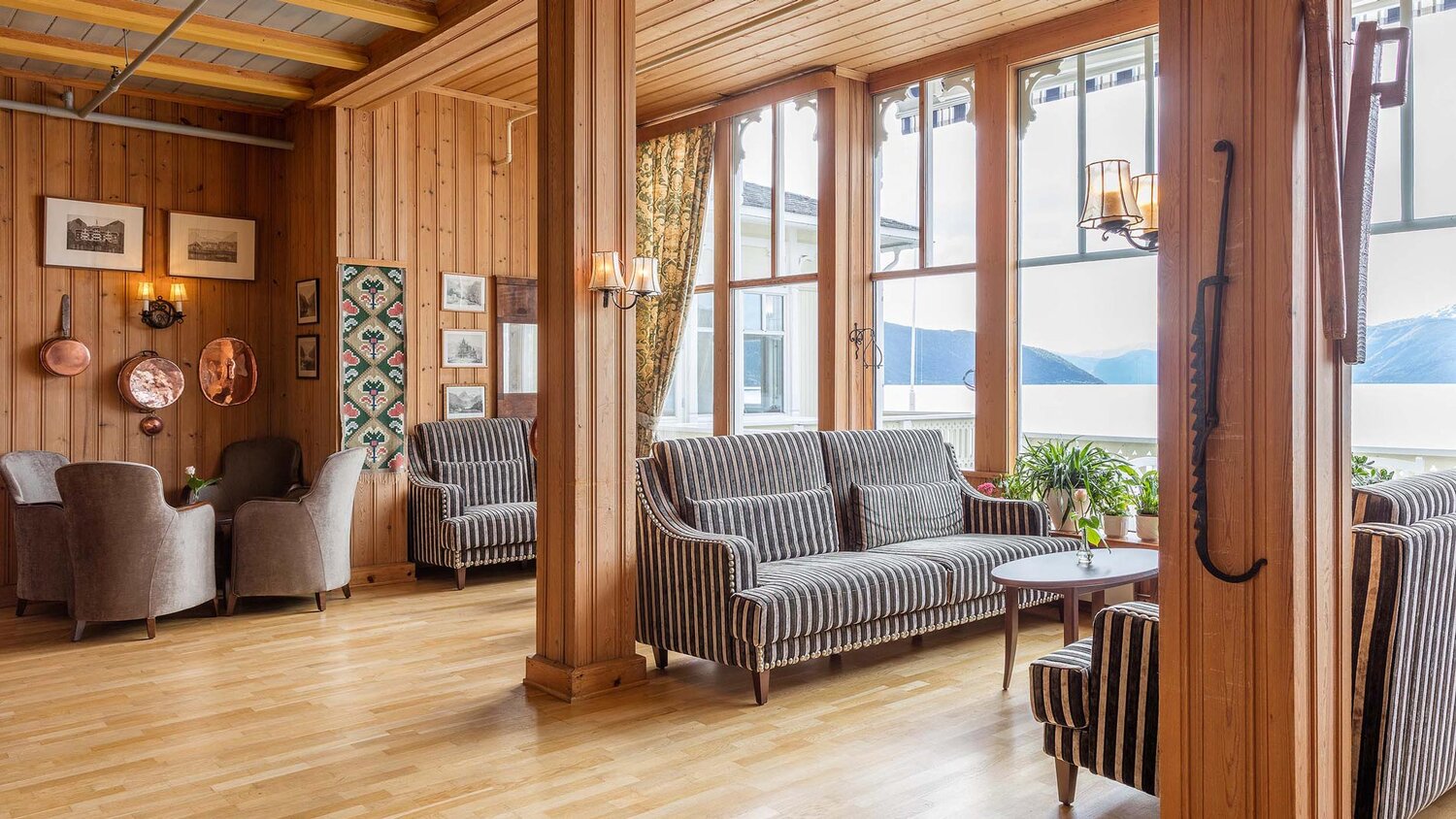 a room with wood walls and a couch and chairs