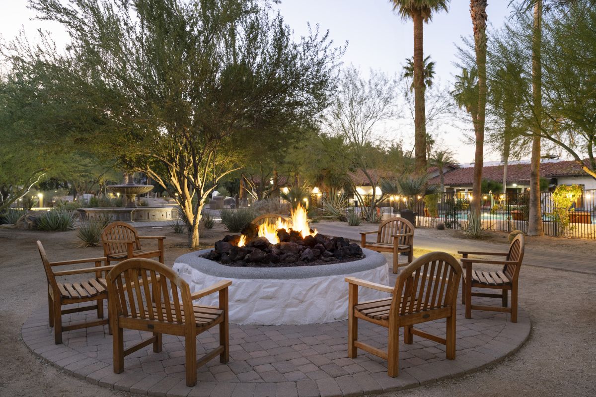 a fire pit surrounded by chairs and trees