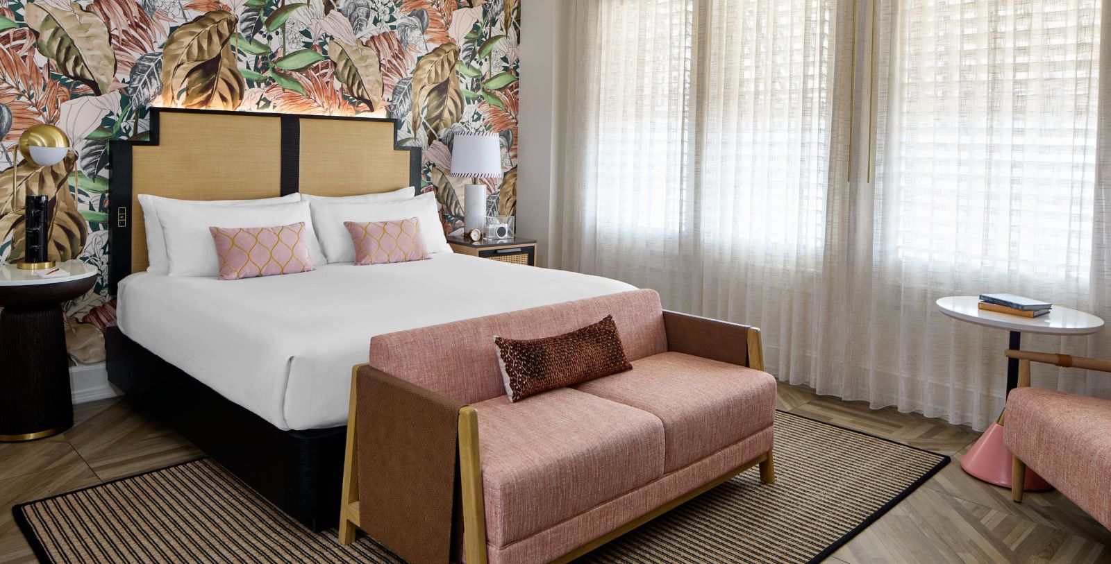 a bed with a pink couch in a room with a floral wallpaper