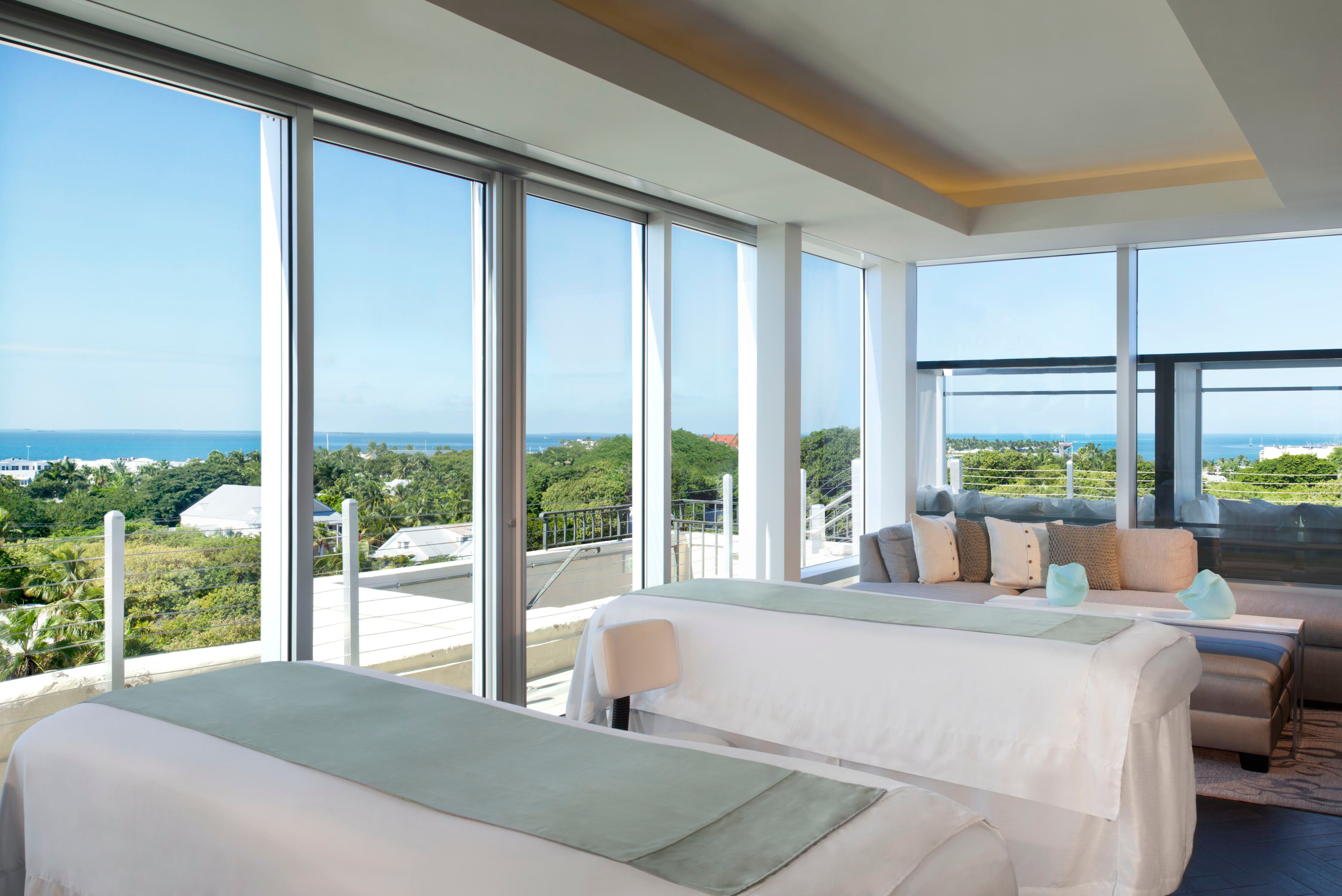 two beds in a room with large windows