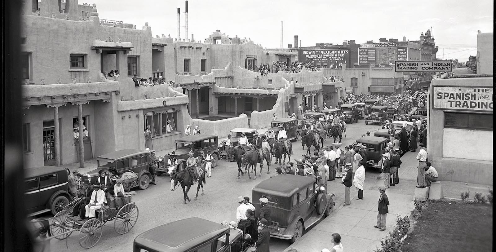 a group of people on a street with horses and cars