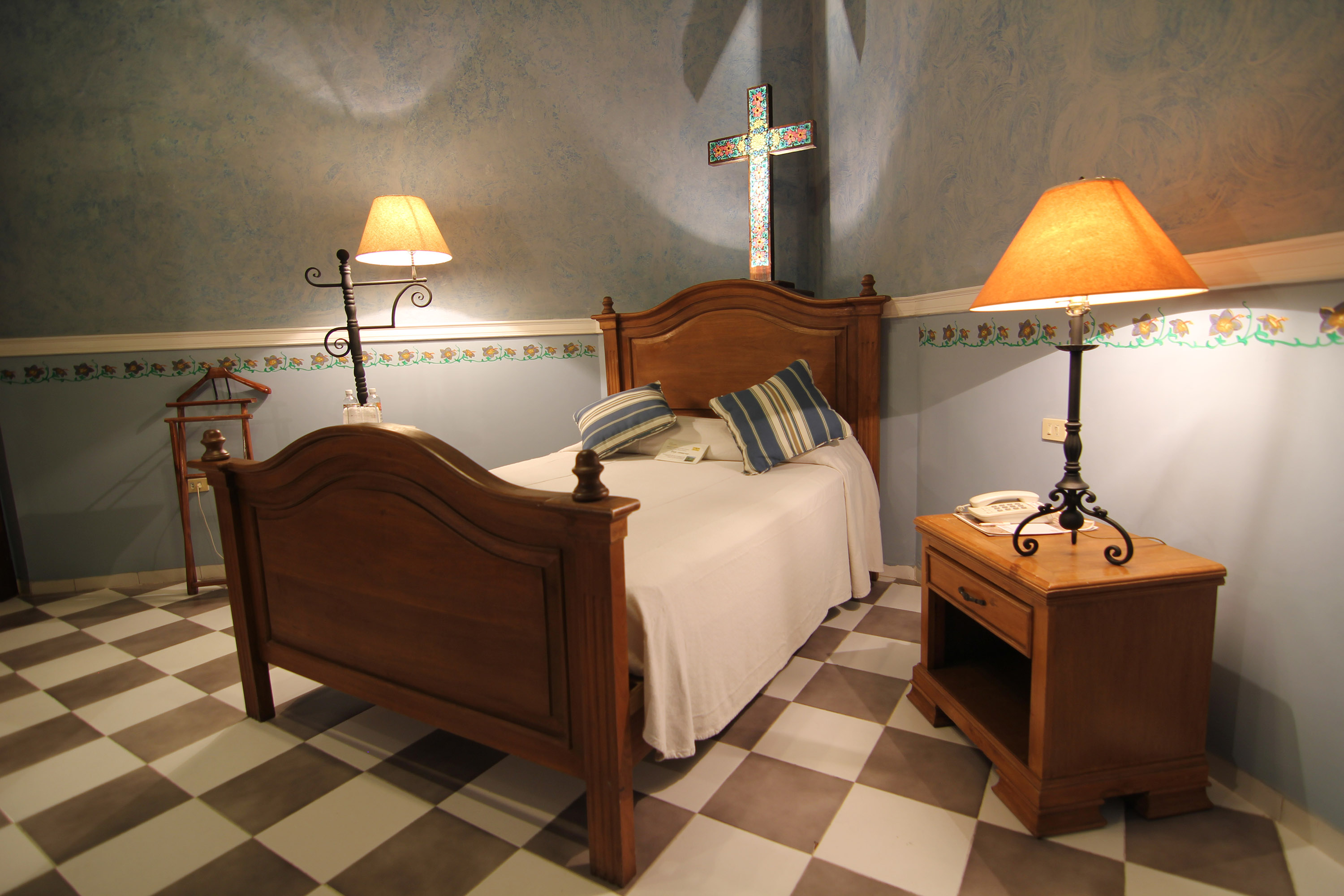 a bed with two lamps and a cross on the wall