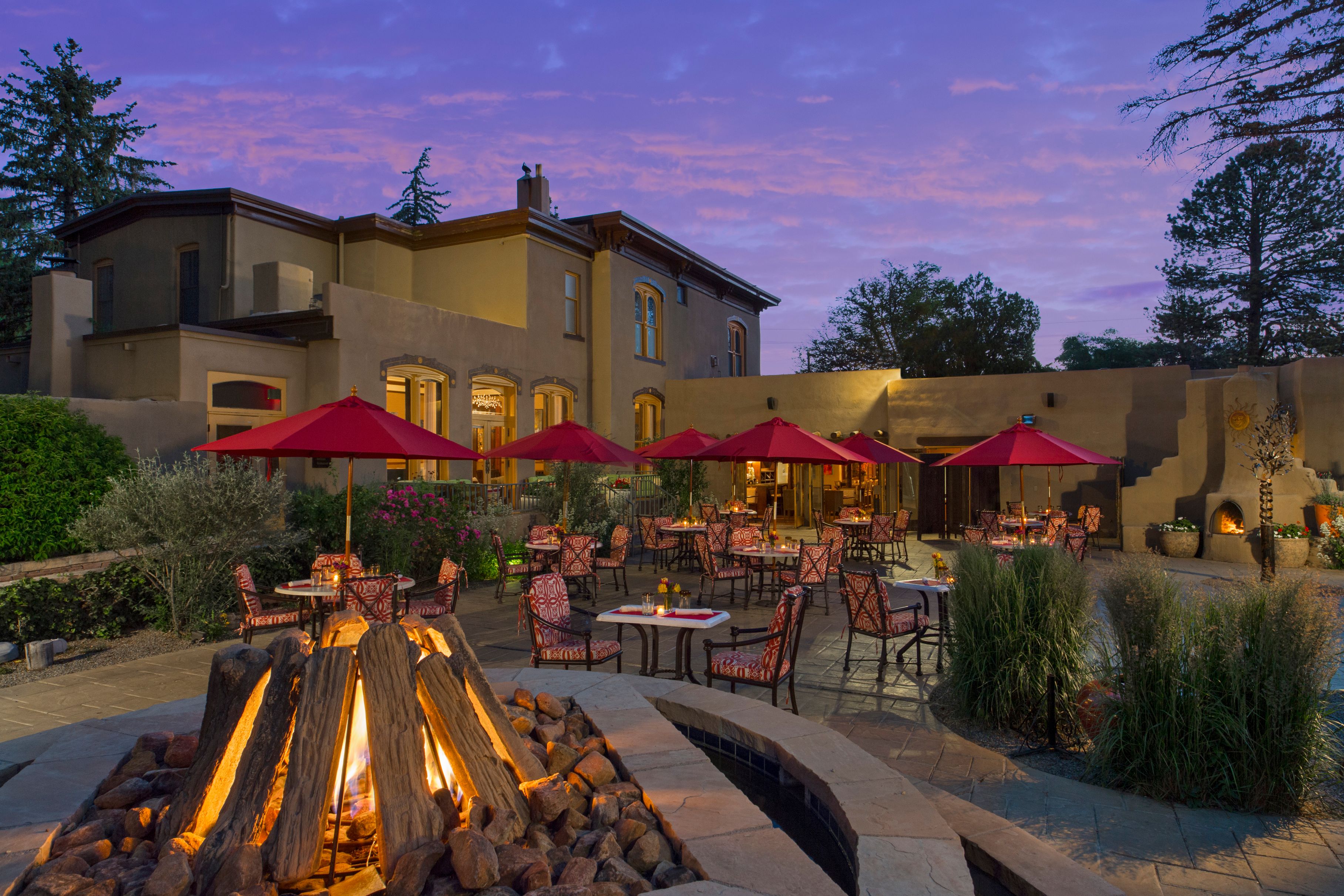 a fire pit with tables and umbrellas in front of a building
