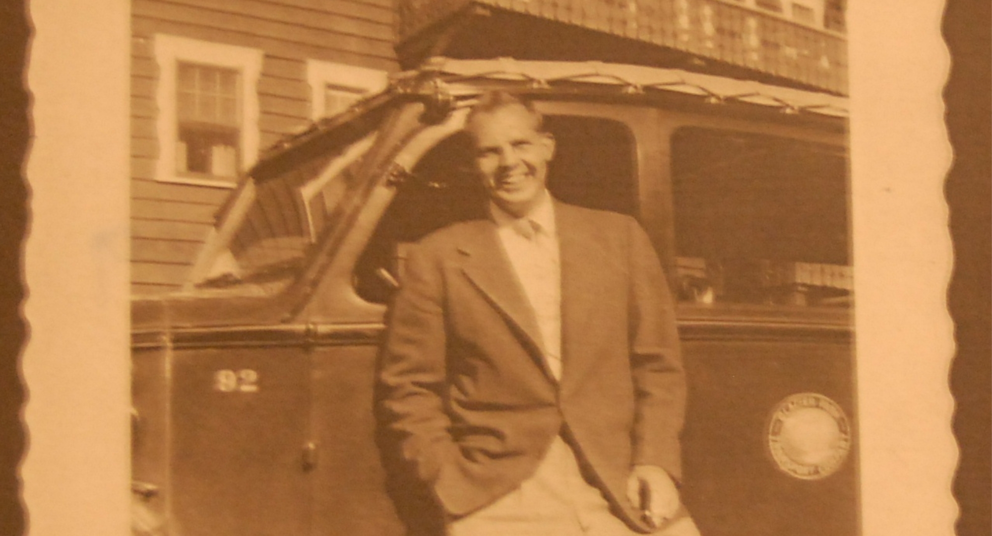 a man in a suit leaning against a car