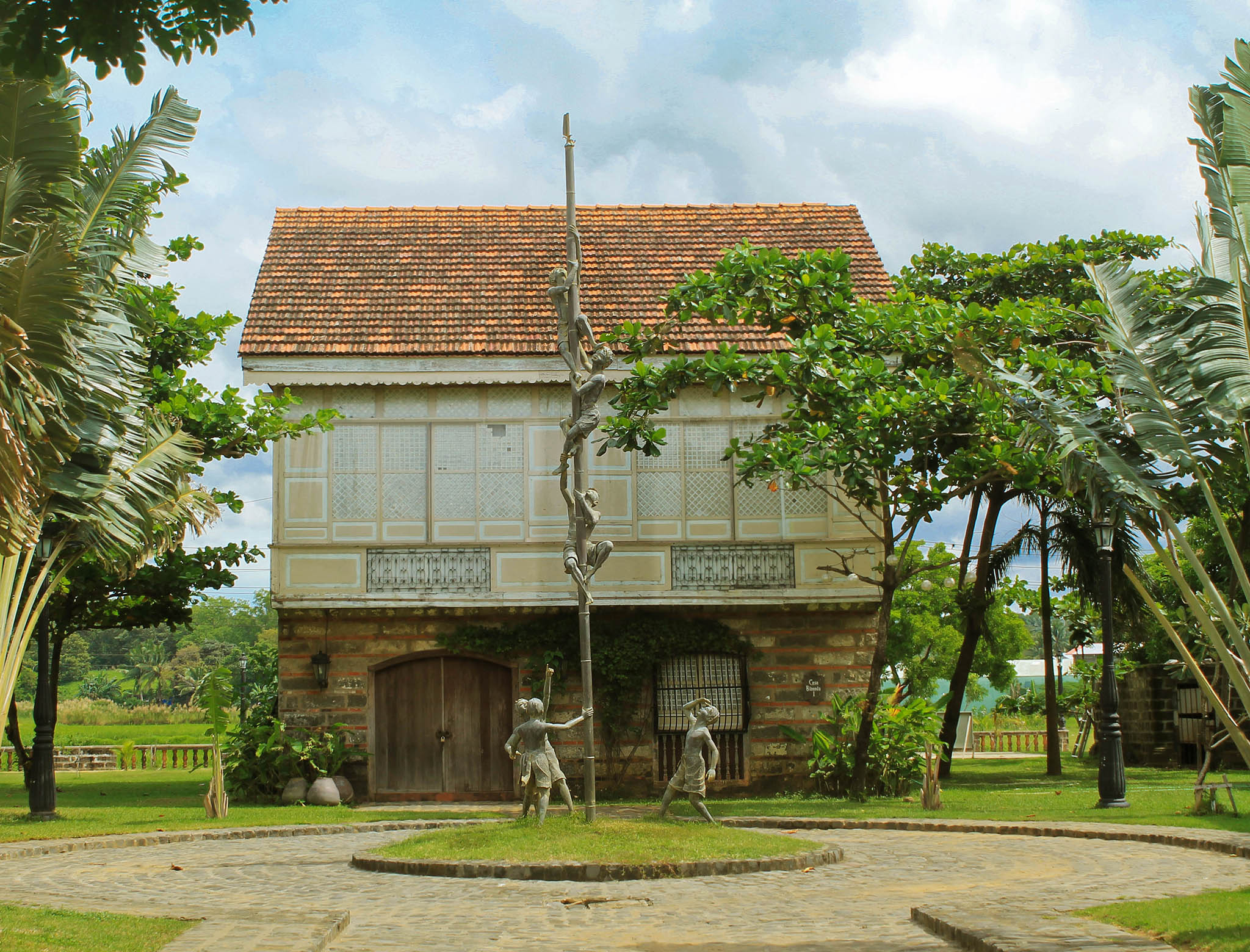 a house with trees and statues in front of it