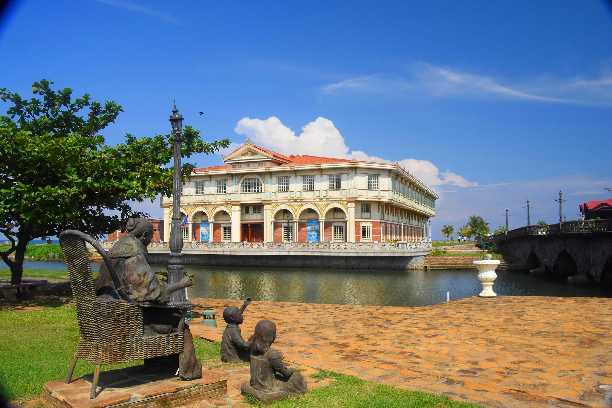 a statue of a man sitting on a bench next to a body of water