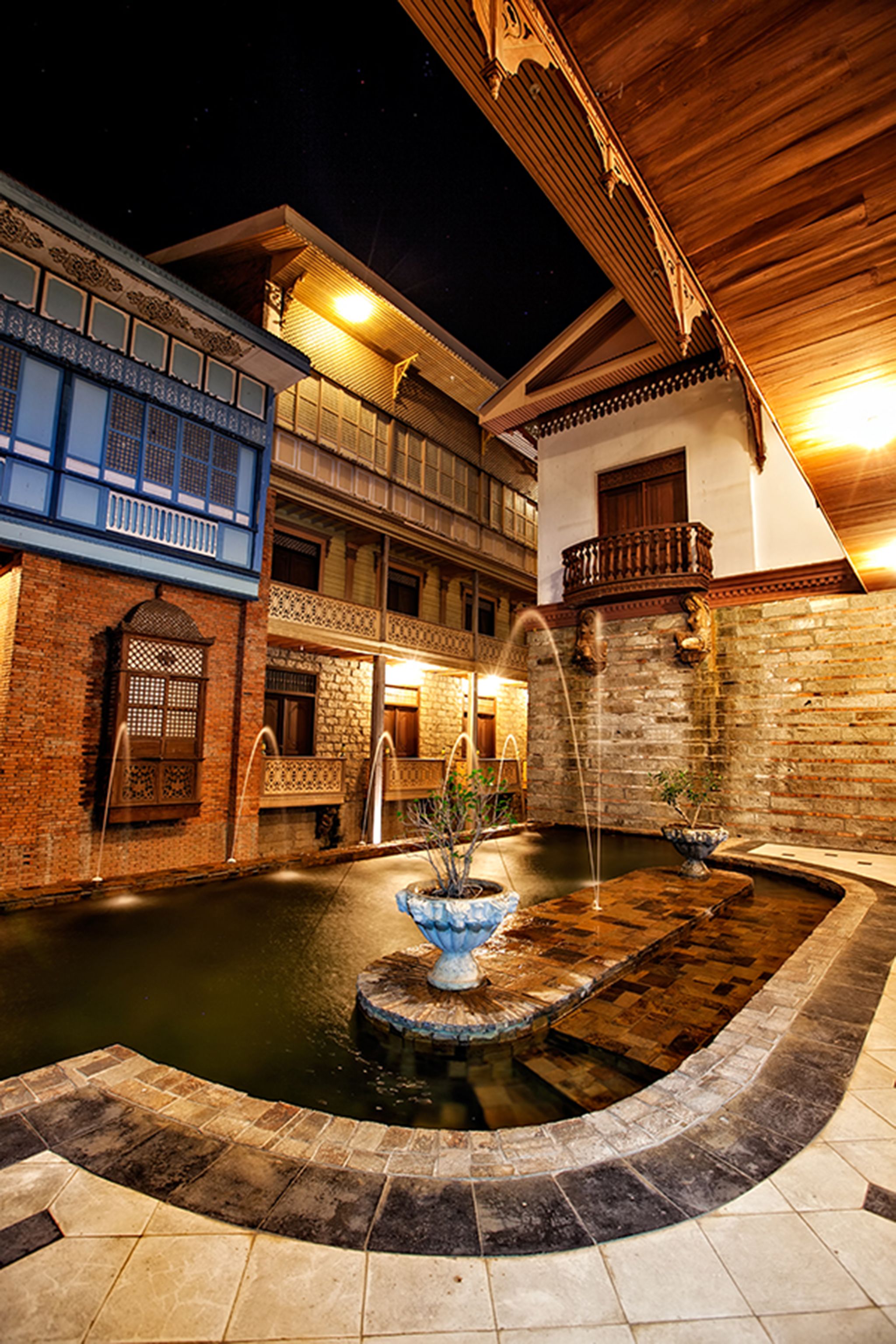 a fountain in a courtyard with buildings and a balcony
