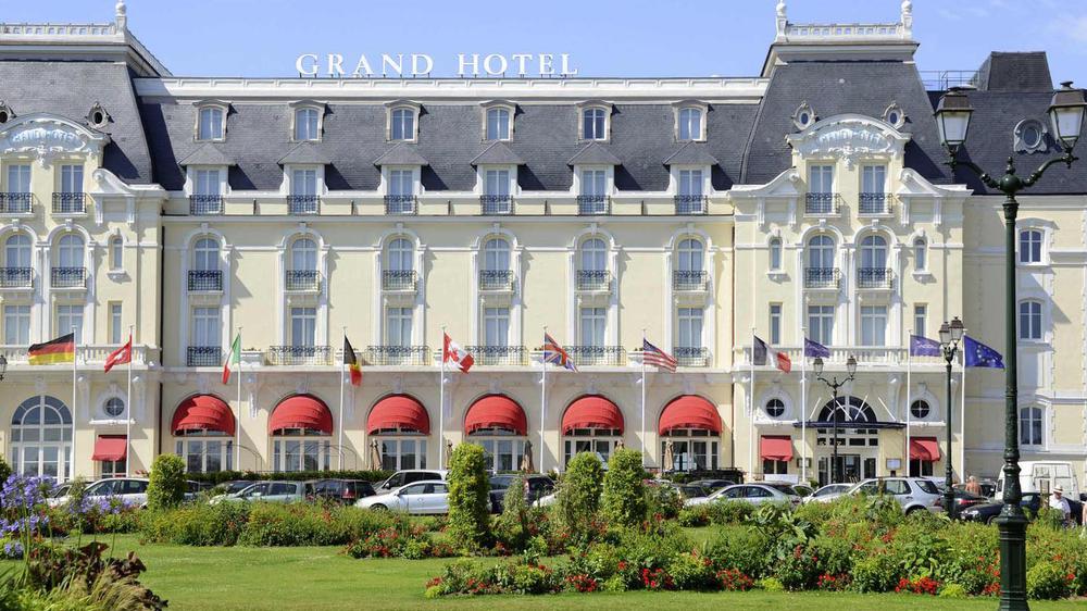 a large white building with red awnings and flags