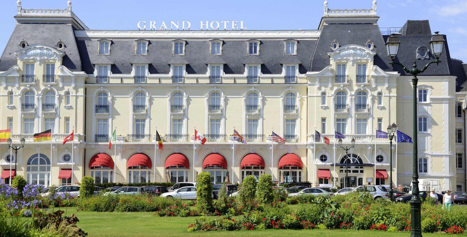 a large white building with red awnings and flags