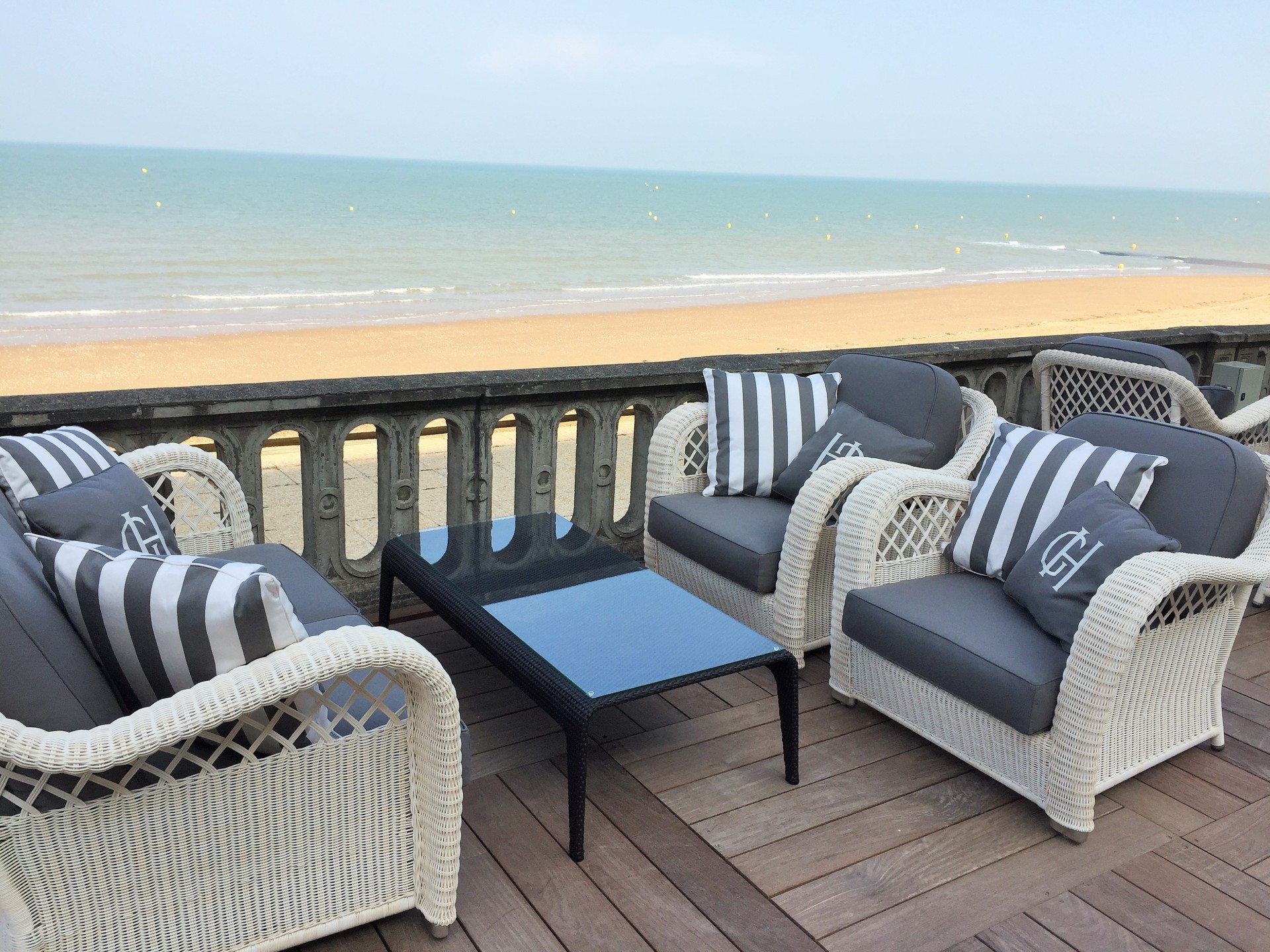 a patio with chairs and a table on a deck overlooking the ocean