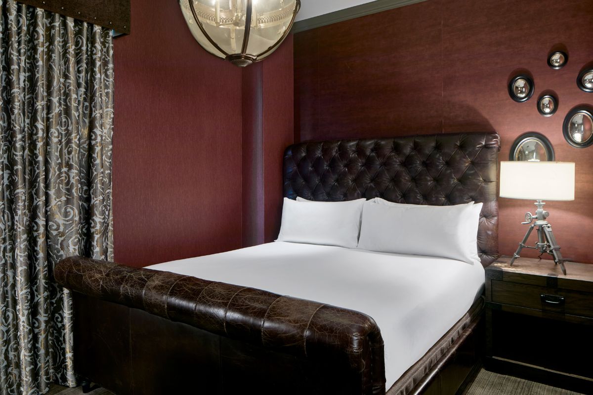 a bed with a leather headboard and a chandelier