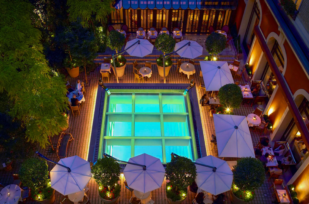 a pool with tables and umbrellas in a courtyard