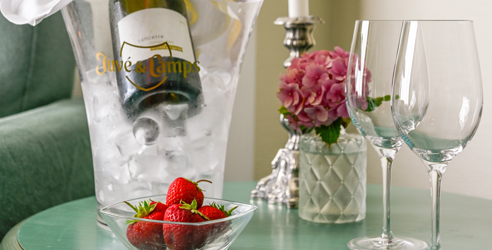 a glass bowl of strawberries and a bottle of wine