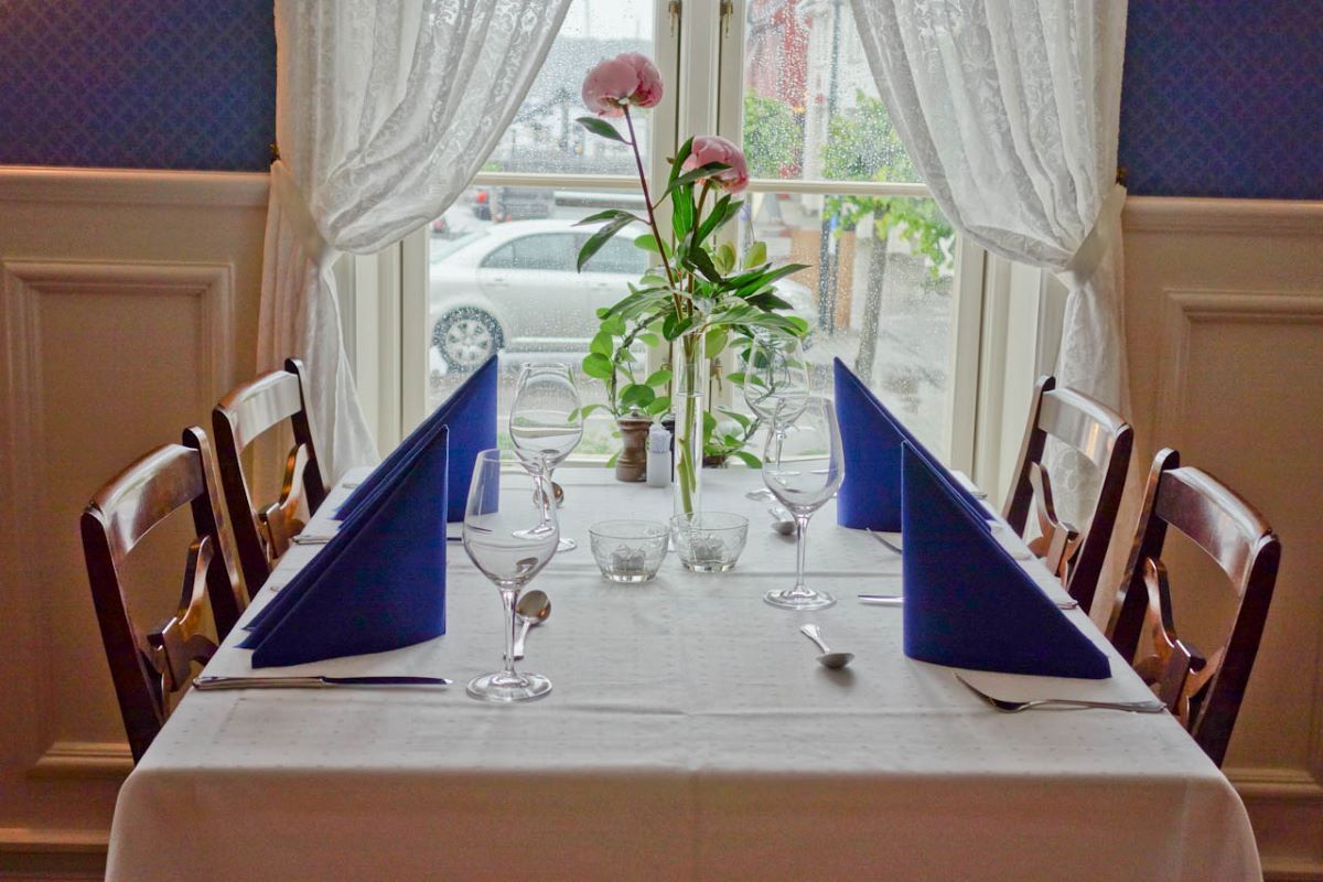 a table with glasses and a vase of flowers in front of a window