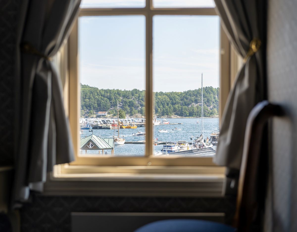 a window with a view of boats on water and trees