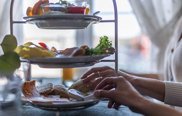 a person's hands reaching for food on a tiered tray