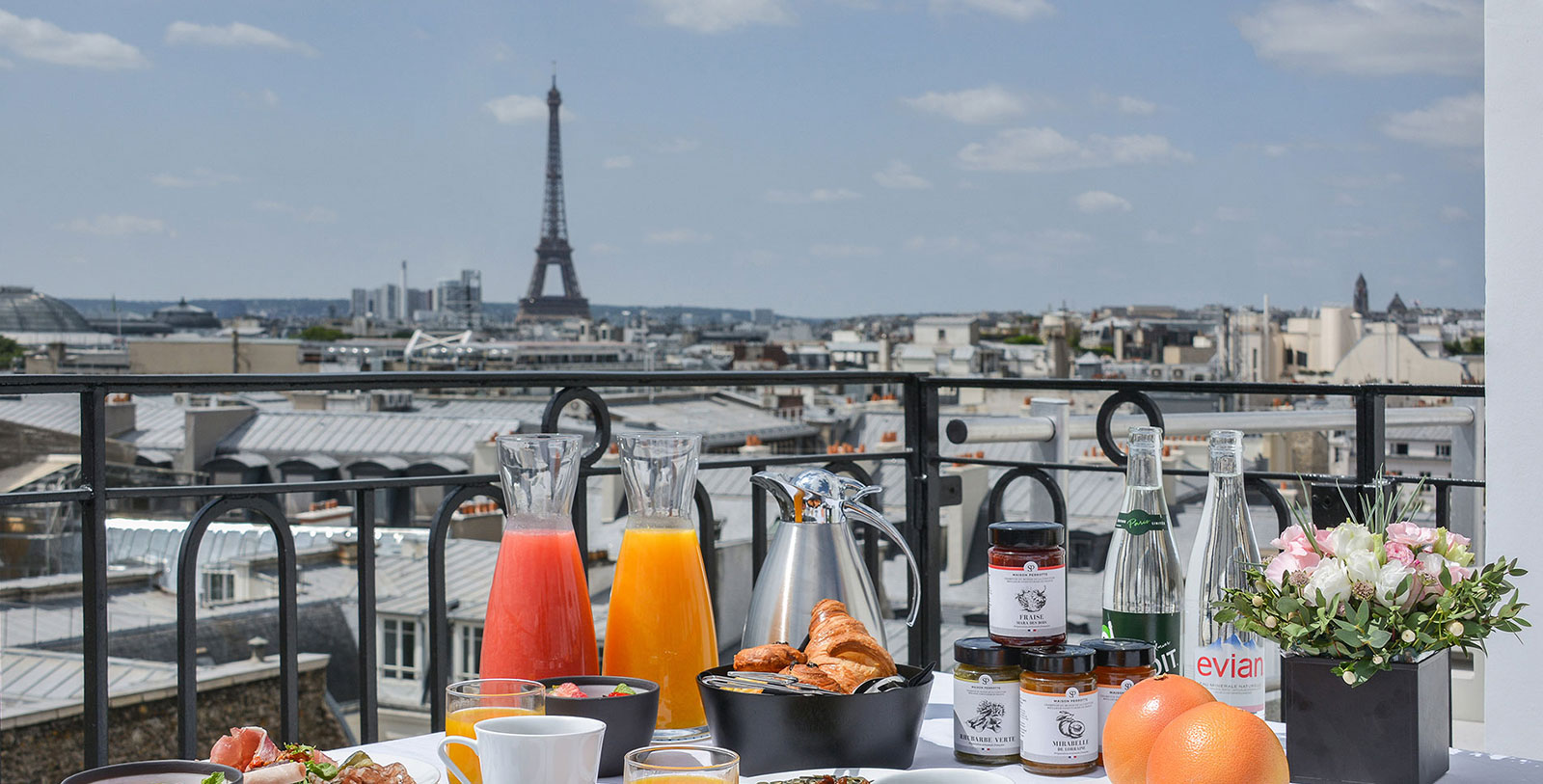 a table with food and drinks on it with a view of the eiffel tower in the background