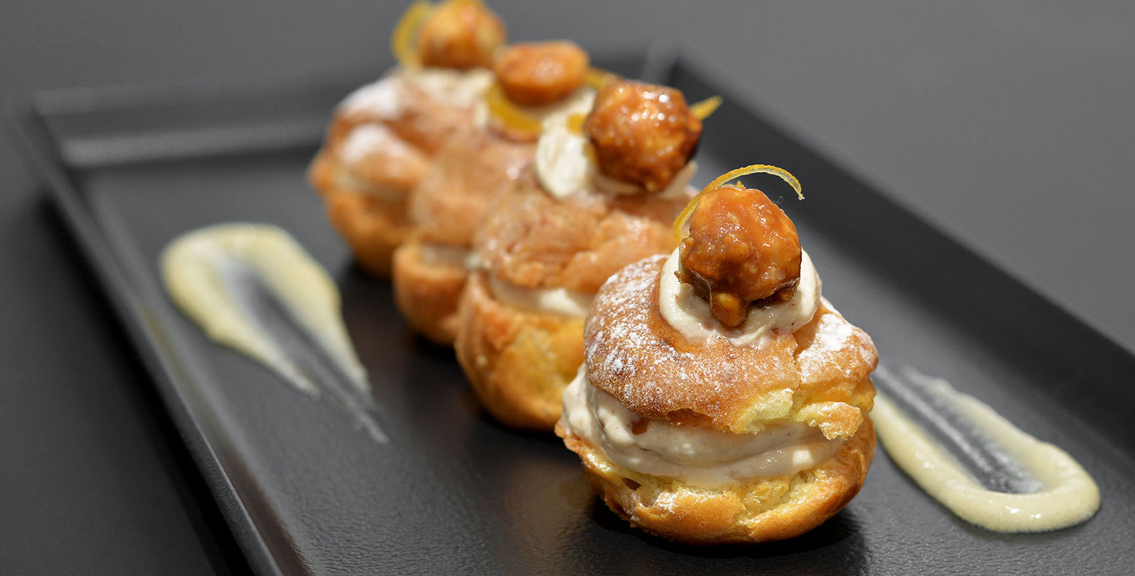 a row of pastries on a black plate
