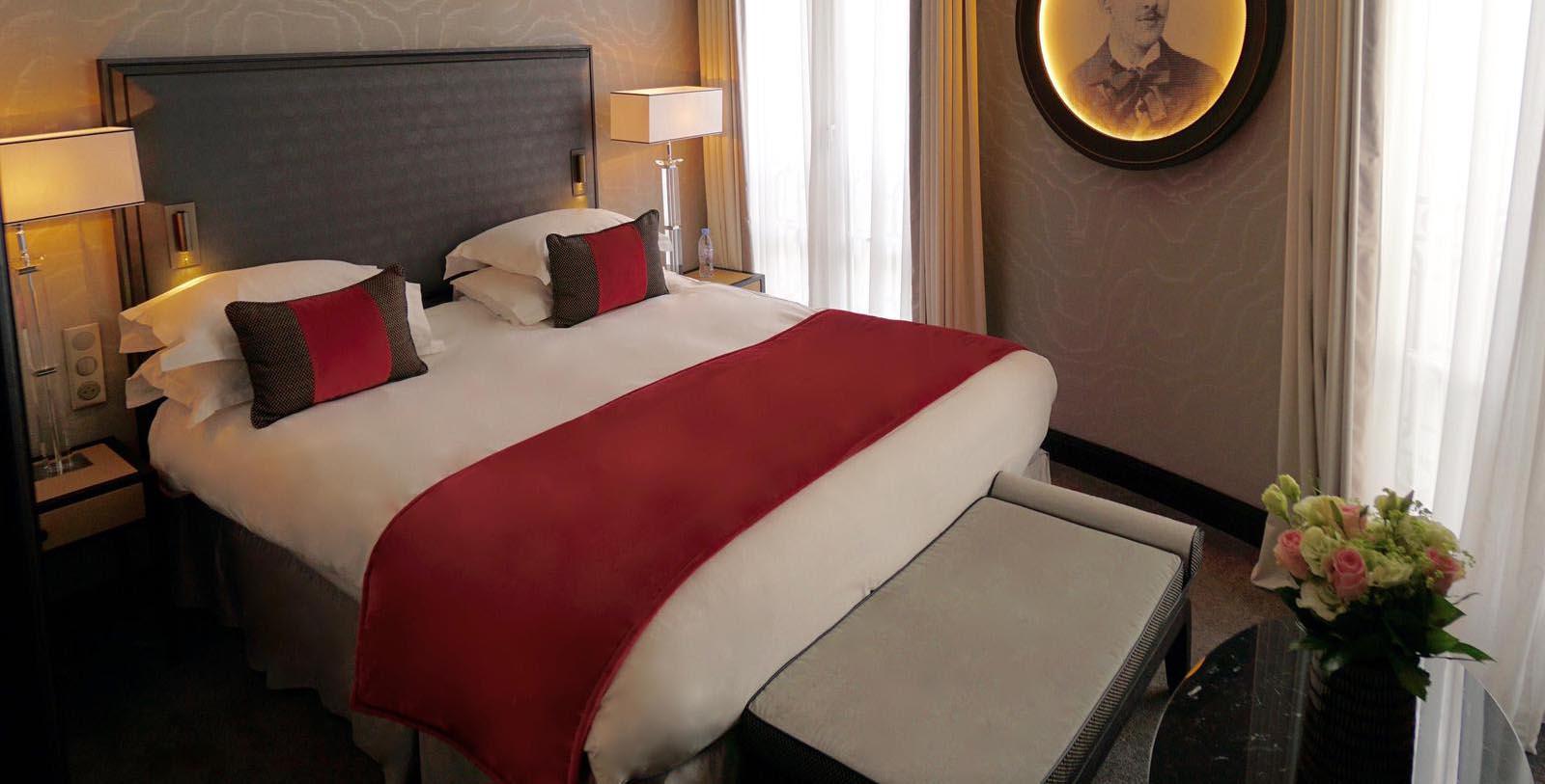 a bed with a red blanket and a lamp