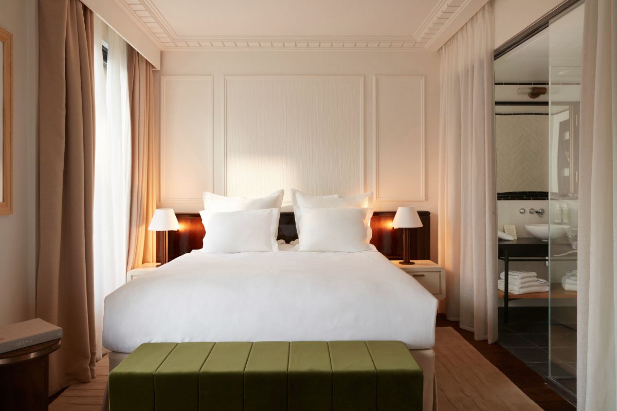 a bed with white pillows and a green ottoman in a room
