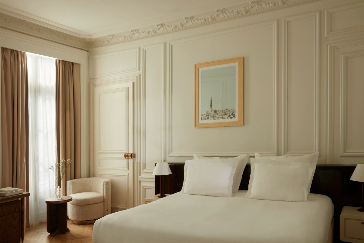 a bed with white sheets and a chair in a room