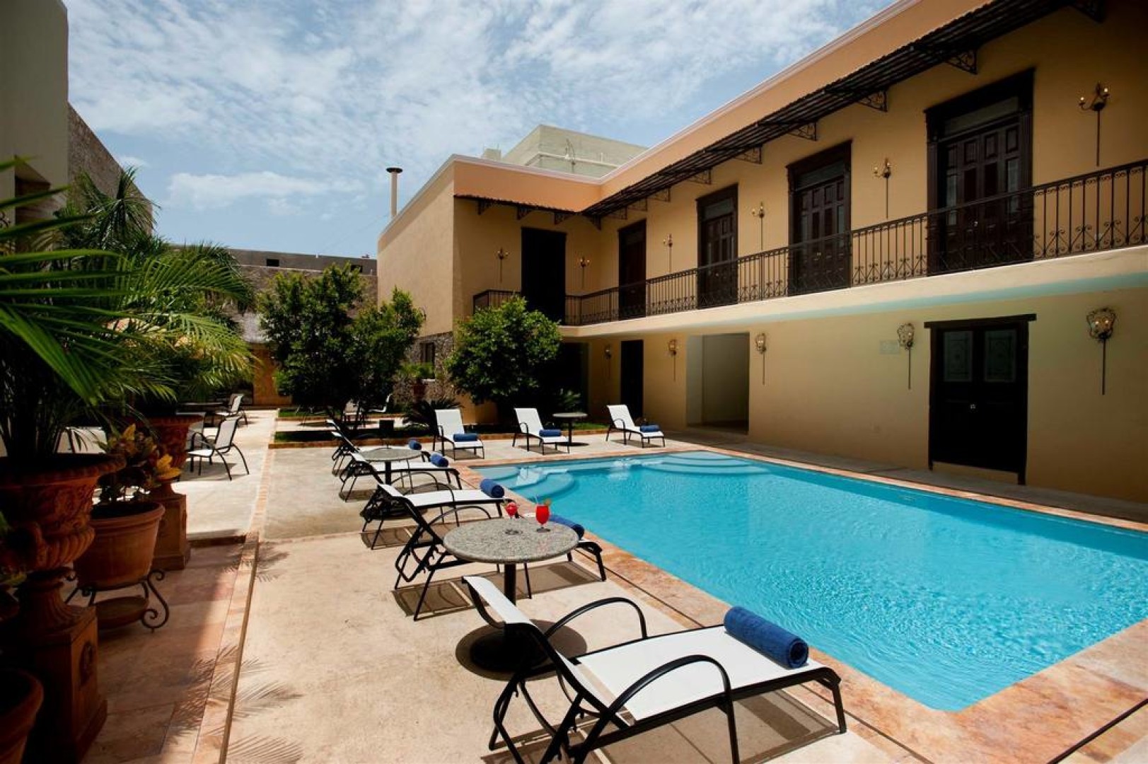a pool with chairs and tables in front of a building