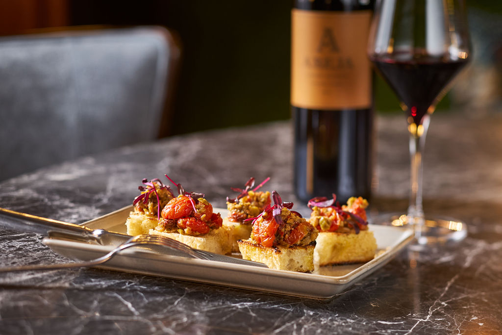 food on a plate next to a glass of wine