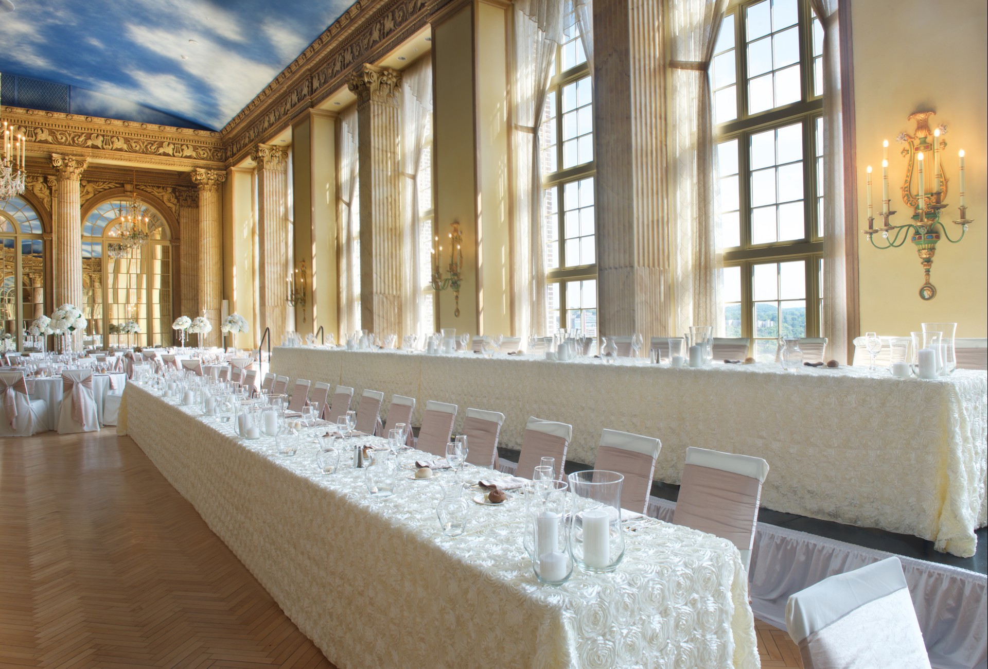 a long white table with white cloths and candles