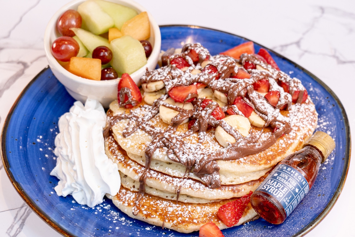 a plate of pancakes with fruit and syrup