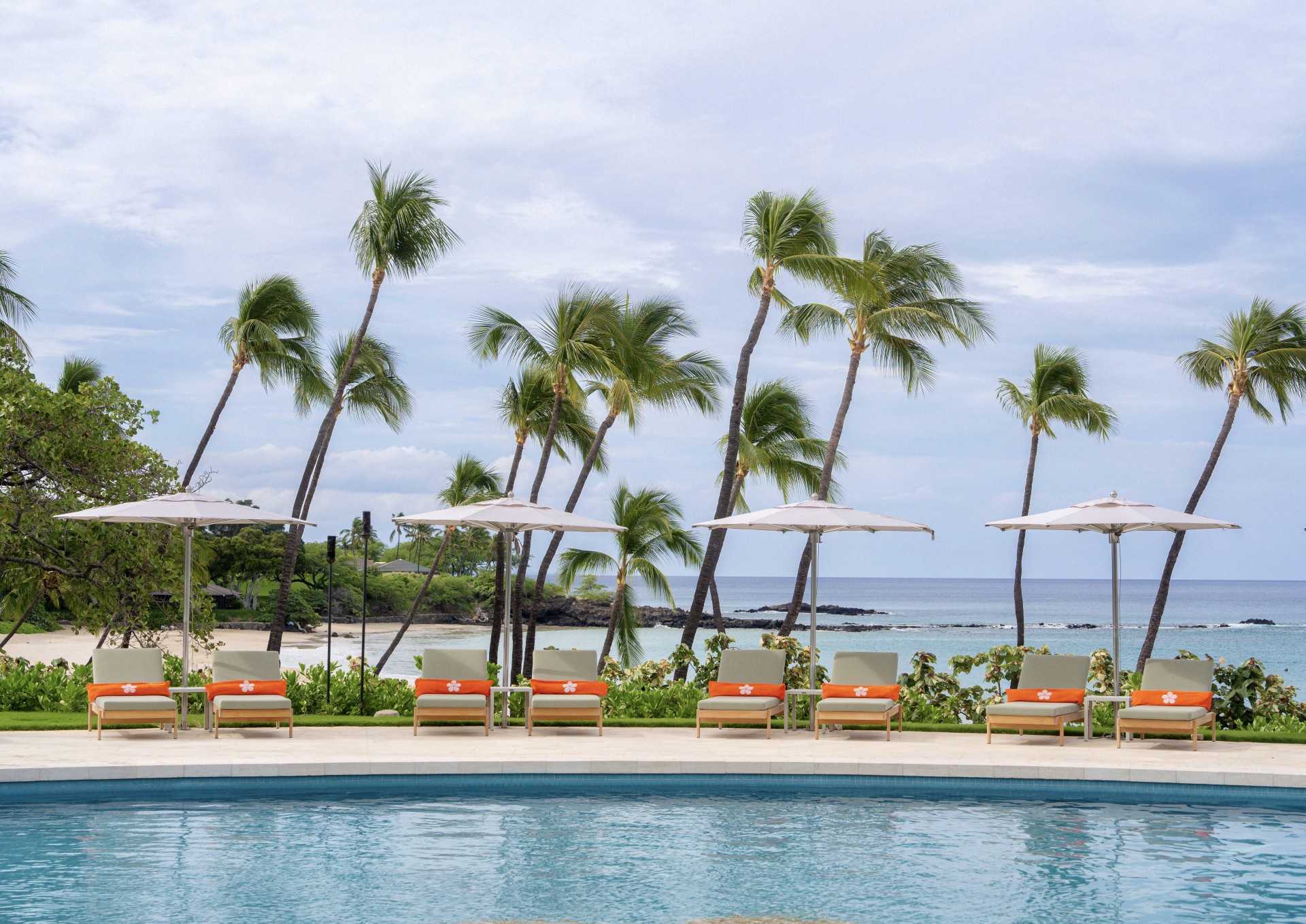a pool with chairs and umbrellas by the water