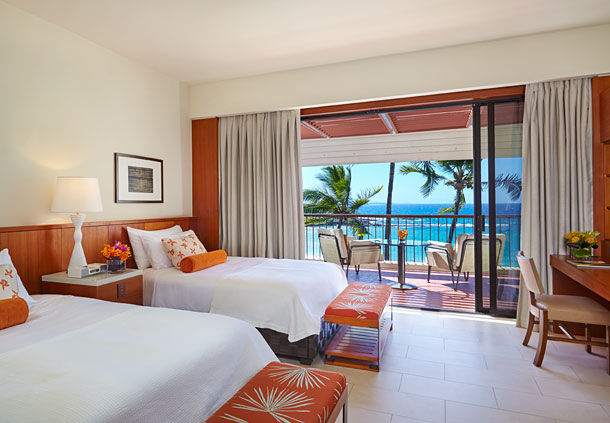 a room with two beds and a balcony overlooking the ocean