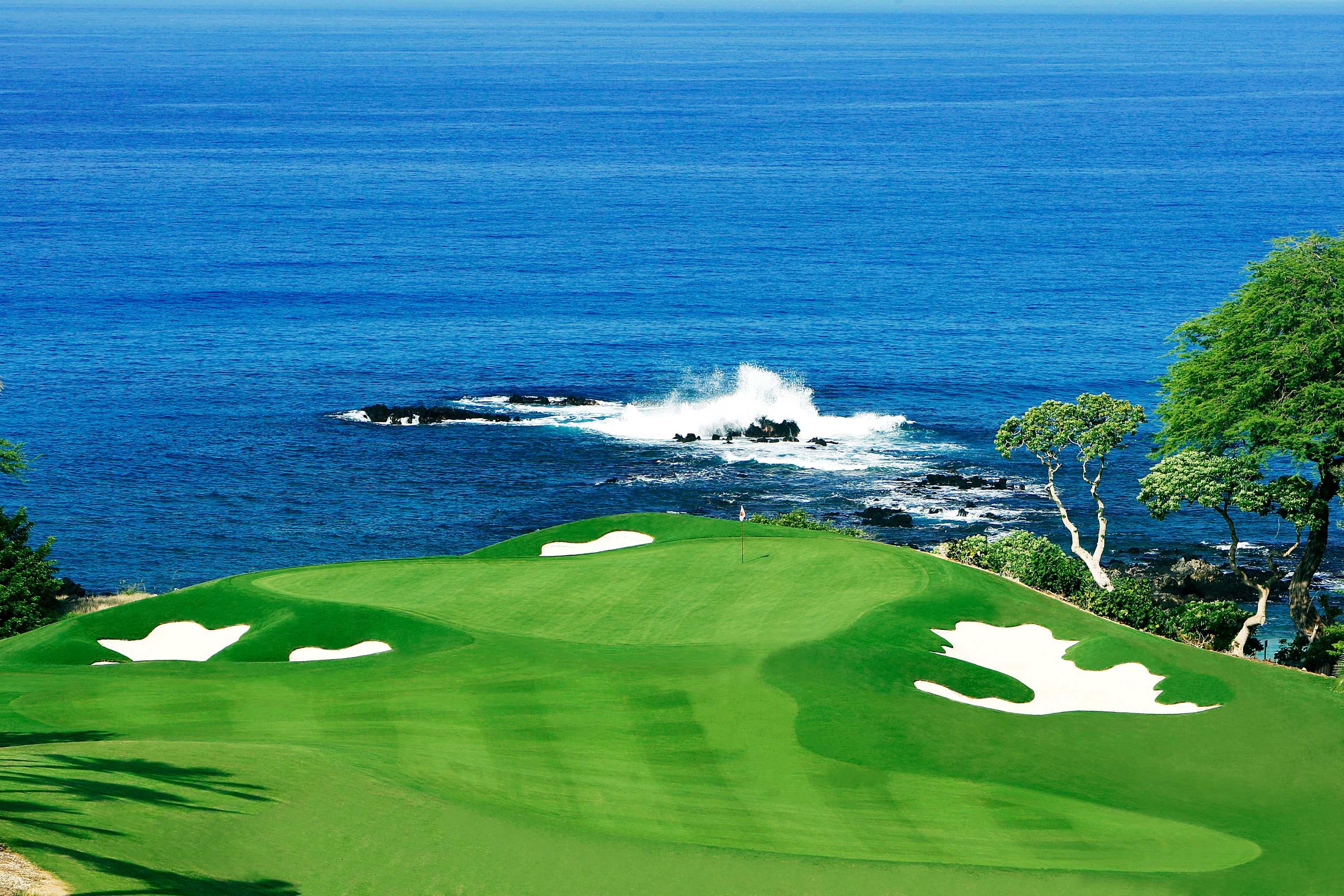 a golf course with a body of water with Pebble Beach Golf Links in the background