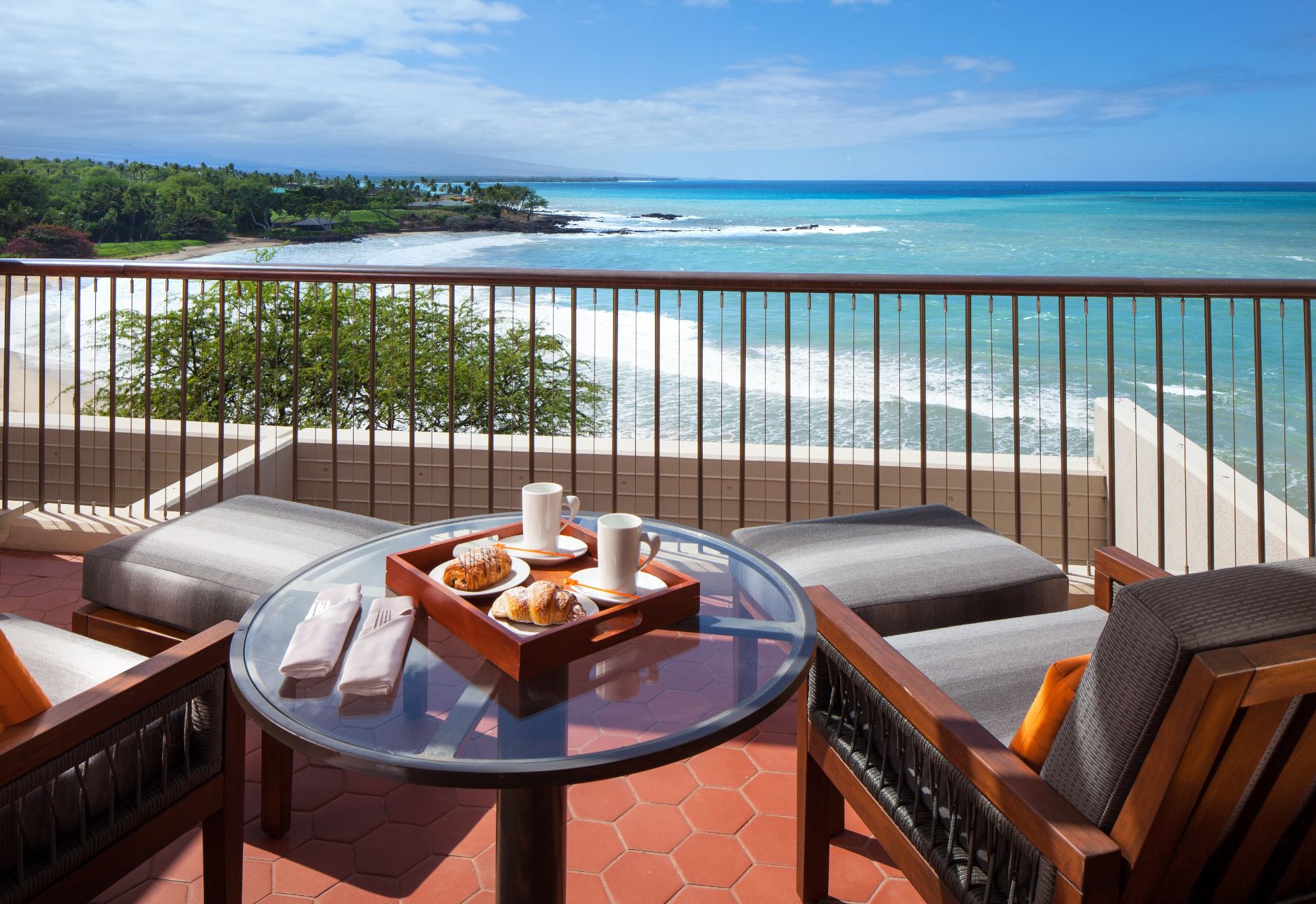 a table with food on it and chairs on a balcony overlooking the ocean