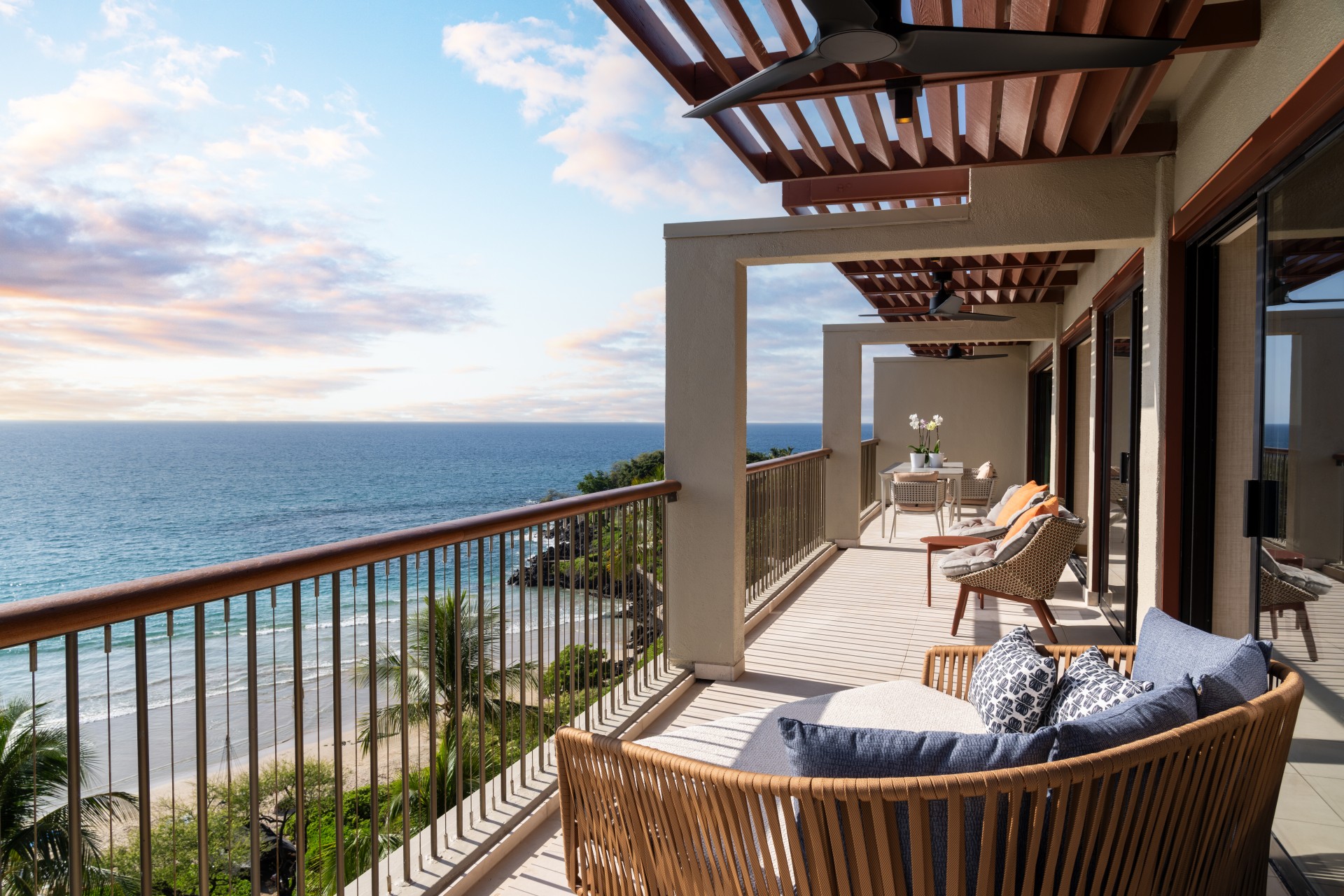 a deck with chairs and a railing overlooking the ocean